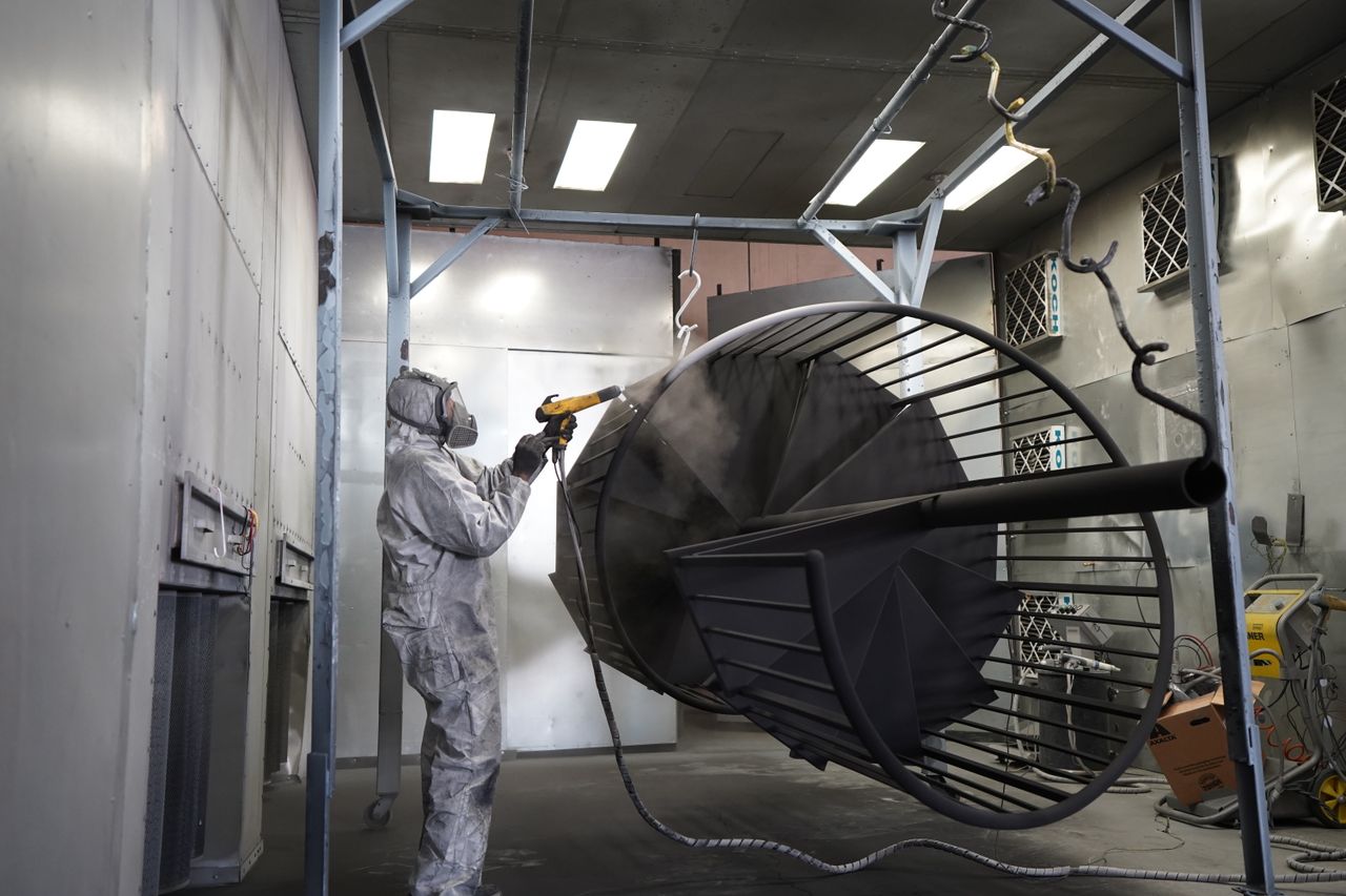 Operator applying powder coating to a large metal fabrication